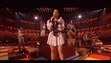 a woman in a white dress sings into a microphone