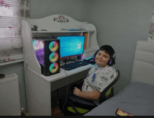 a boy wearing headphones is sitting in front of a computer monitor