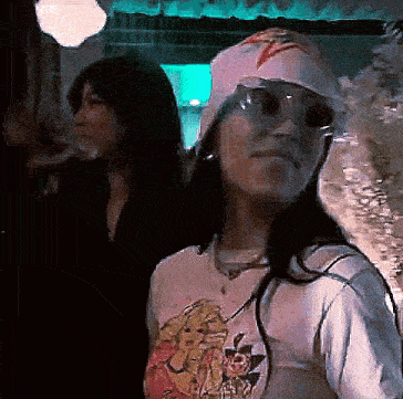 a woman wearing a hat and sunglasses is standing next to another woman .