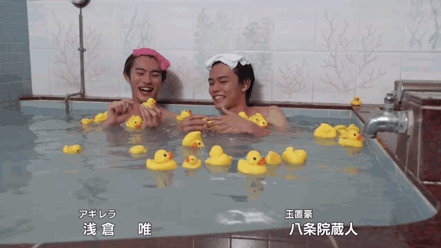 two men are playing with rubber ducks in a bathtub with chinese writing