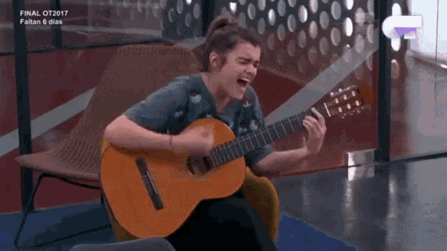 a woman is singing while playing a guitar in front of a sign that says final