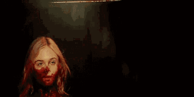 a woman with blood on her face is holding a knife .