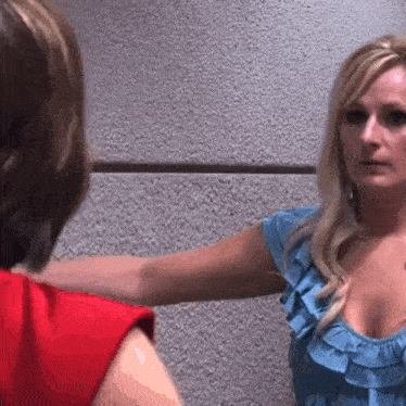 a woman in a blue ruffled top is standing next to another woman in a red top