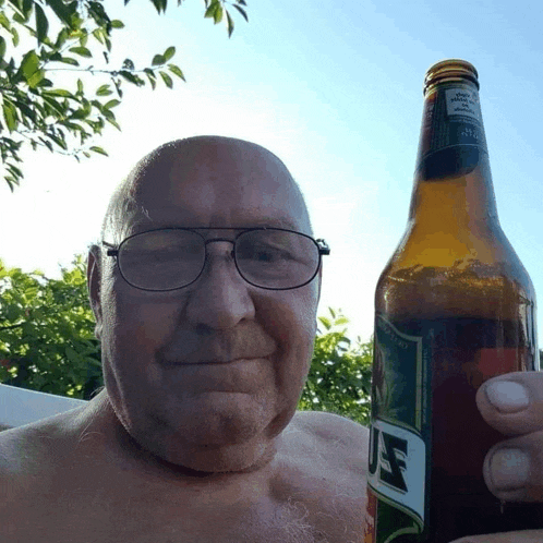a shirtless man is holding a bottle of u.f. beer in his hand