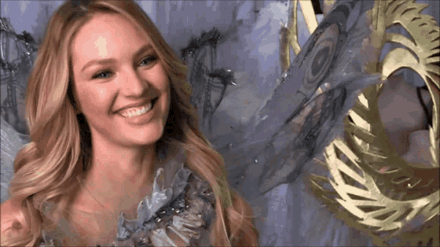 a woman in a blue dress is smiling in front of a purple wall