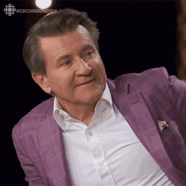 a man in a purple suit and white shirt is smiling with #cbcdragonsden in the corner