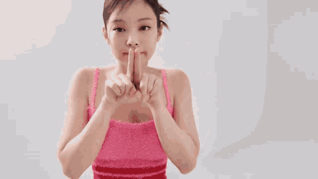 a woman in a pink tank top is smiling and waving her hands