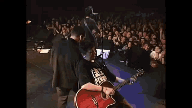 a man playing a guitar with a shirt that says ' fuck prison ' on it