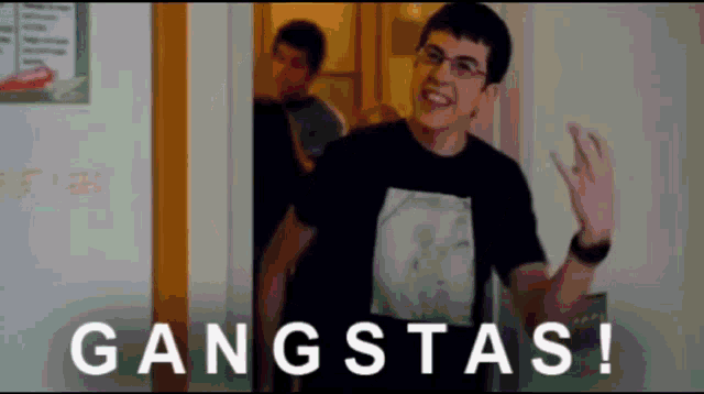 a man wearing glasses and a black shirt that says gangstas on it