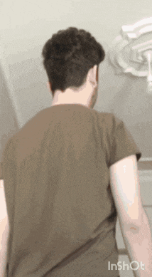 a man in a brown t-shirt is standing in a room .