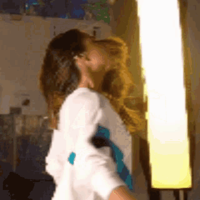 a woman is dancing in front of a yellow light .
