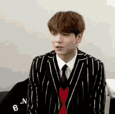 a man in a suit and tie is standing in front of a wall with the letter b on it .