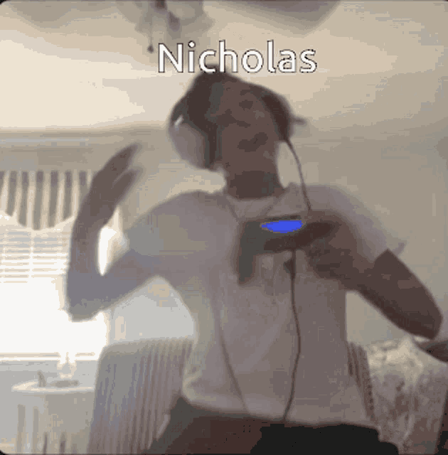 a man wearing headphones is playing a video game and the name nicholas is on the bottom right
