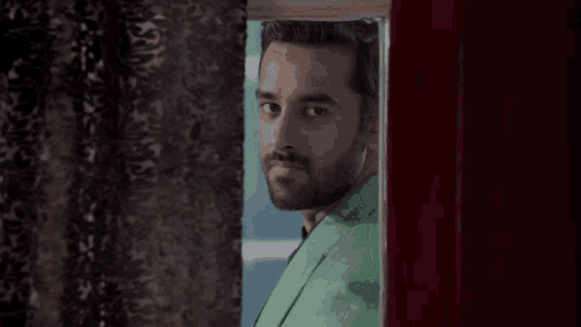 a man in a green jacket is looking out a window