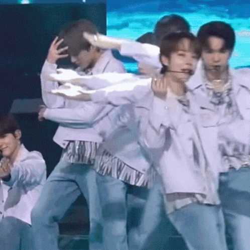 a group of men are dancing on a stage and one of them has a microphone in his mouth