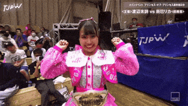 a girl in a pink dress is standing in front of a tjpw sign ..