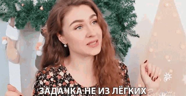 a woman in a floral dress is standing in front of a christmas tree and talking in a foreign language .