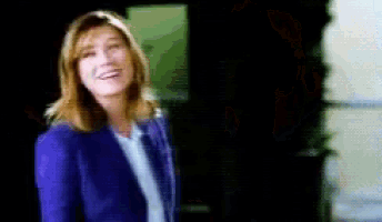 a woman in a blue jacket is smiling in a dark room