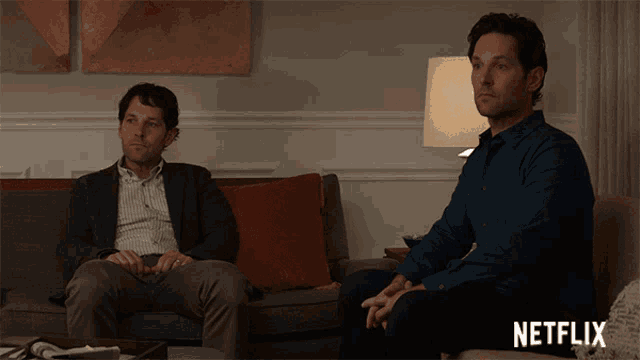 two men sitting on a couch with a netflix logo on the bottom