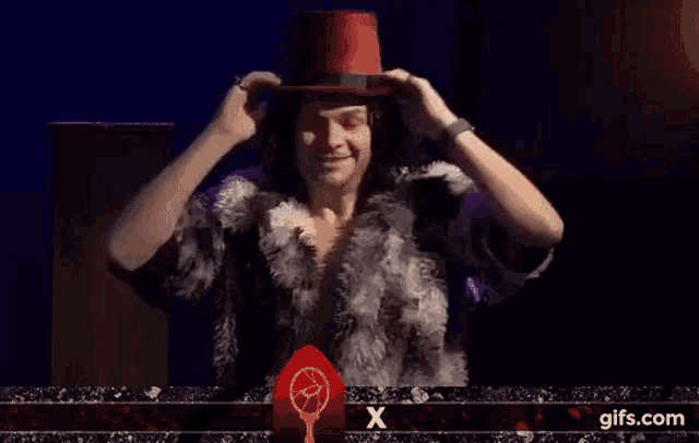 a man wearing a top hat and a fur coat is standing on a stage .