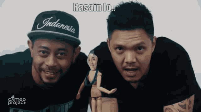 a man wearing a indonesia hat stands next to a man holding a puppet