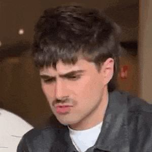 a man with a mustache is making a funny face while wearing a leather jacket .