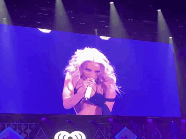 a woman singing into a microphone on a stage at iheart radio