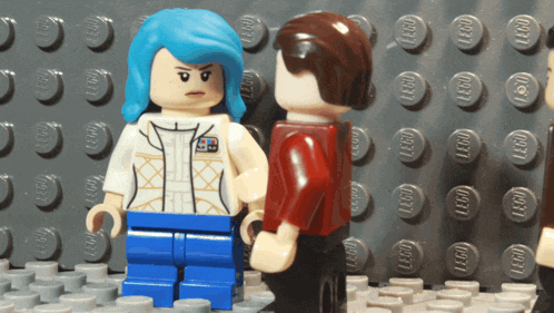 a woman with blue hair is standing next to a man with brown hair on a lego board