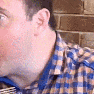 a man in a plaid shirt is eating a meal with a fork .