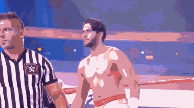 a man in a striped shirt with a w on it stands next to a referee