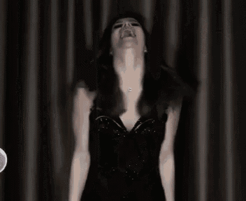 a woman is standing next to a door in a dark room with a reflection of her face in the mirror .