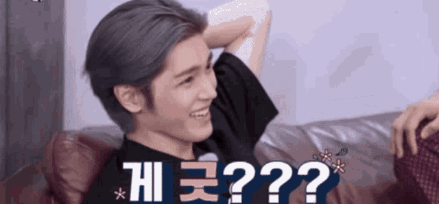 a man is sitting on a couch with his hand behind his head and the words " ? " above him