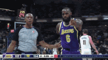 a basketball player wearing a lakers jersey is standing next to a referee