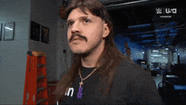 a man with long hair and a mustache is wearing a black shirt that says n & n on it