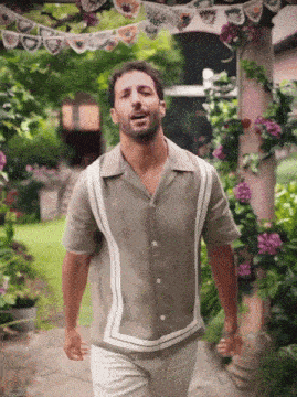a man in a tan shirt and white pants is walking in a garden