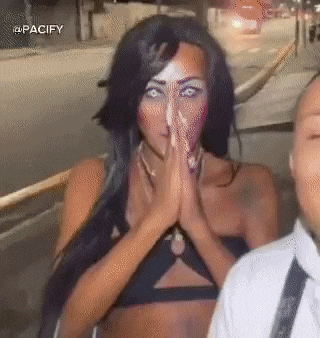 a woman is praying with her hands folded in front of her face while standing next to a man .