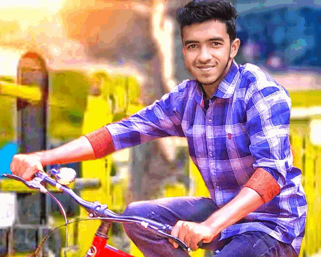 a young man in a blue and white plaid shirt is riding a red bicycle