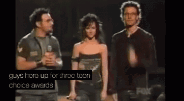 two men and a woman standing on a stage with the words " guys here up for three teen choice awards "