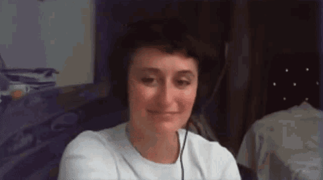 a woman wearing headphones and a white shirt smiles for the camera