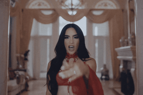 a woman in a red top is pointing her finger at the camera