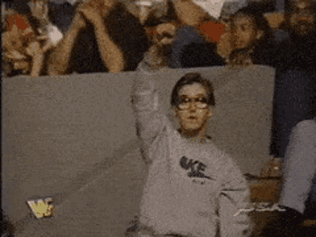a young boy wearing a nike sweatshirt stands in front of a crowd of people