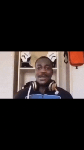 a man wearing headphones is smiling in front of a shelf with a skull on it