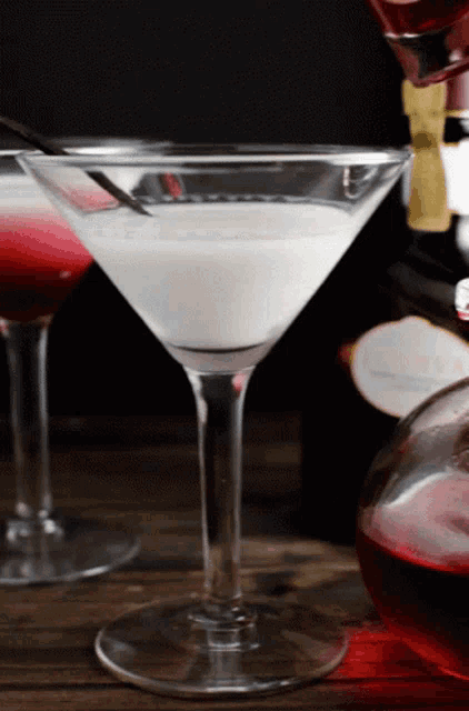 a martini is being poured into a glass with a spoon in it