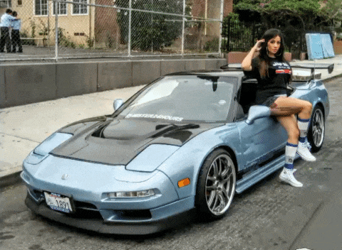 a woman sits on the hood of a car with a license plate that says ' 1337 ' on it