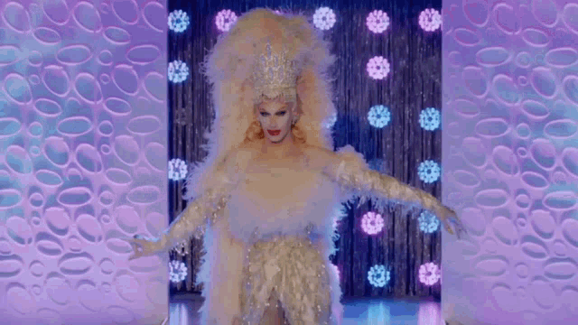 a drag queen wearing a white feathered dress and a crown
