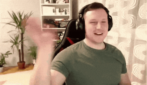 a man wearing headphones and a green shirt is waving