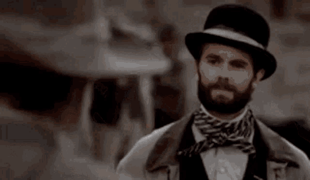 a man with a beard wearing a top hat and bow tie is standing in front of the word well .