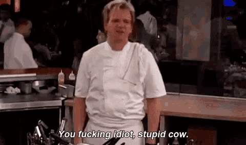 a man in a chef 's uniform is standing in a kitchen talking to someone .