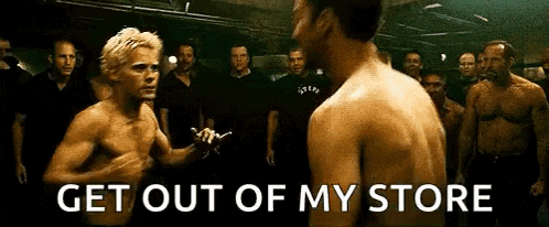 a group of men are standing around a man without a shirt in a boxing match .