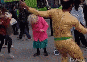 a woman in a pink jacket is dancing with a man in a yellow bodysuit